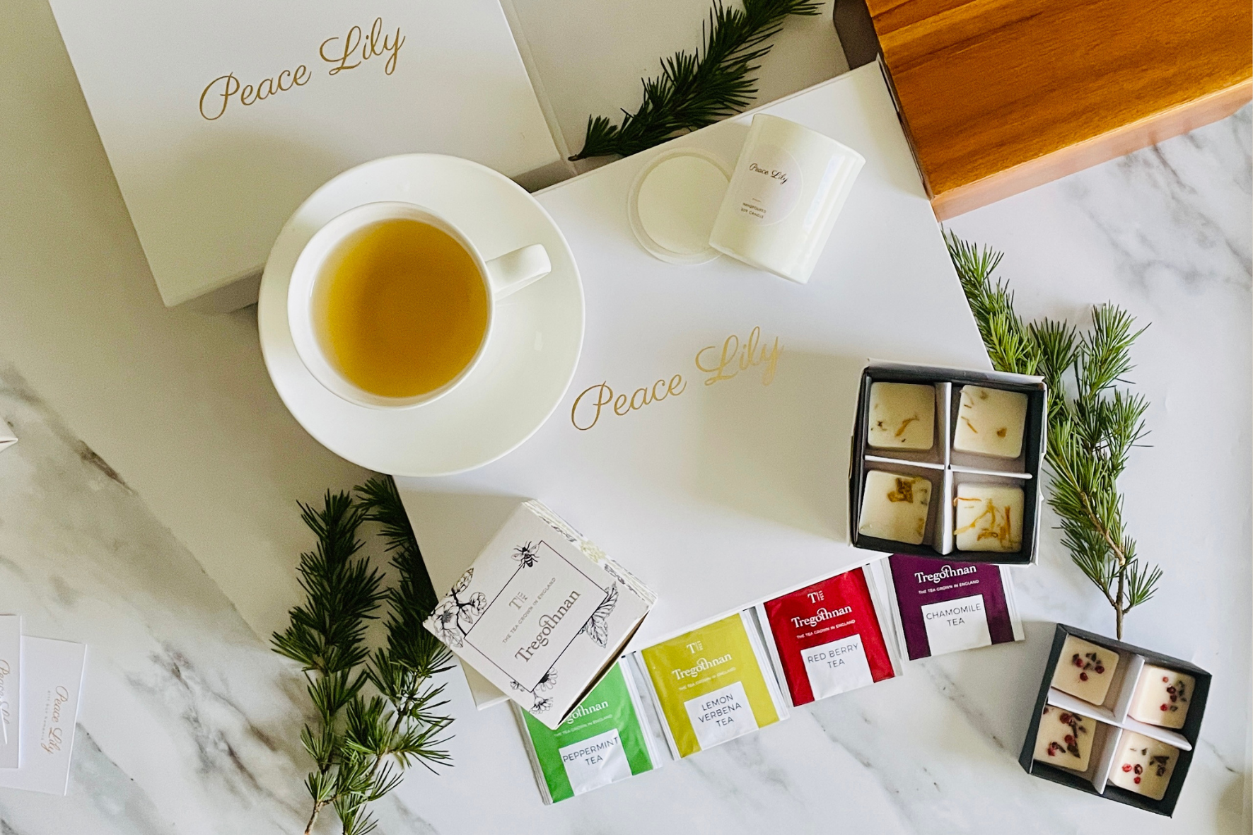 Luxury scented candle gift set with glass candle holder, luxury white box and ribbon and postcard for personalised message. Peace Lily plant in background.