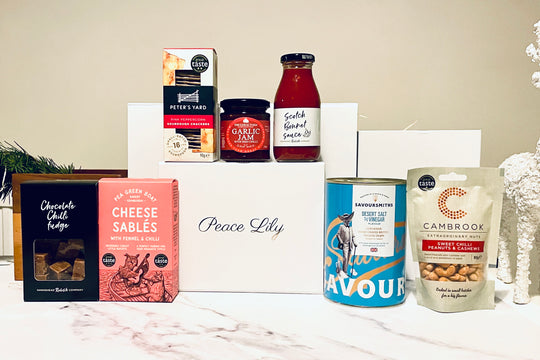 Assorted food products including a can, bottle, and packets on a white surface with a neutral background.